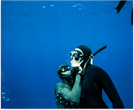 The instructor teaches the diver underwater
